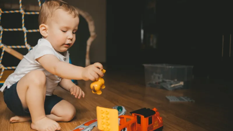 Kleiner Junge spielt mit einer Lego Duplo Eisenbahn