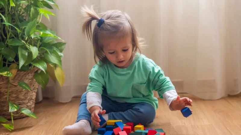 Kleines Mädchen spielt mit Bausteinen
