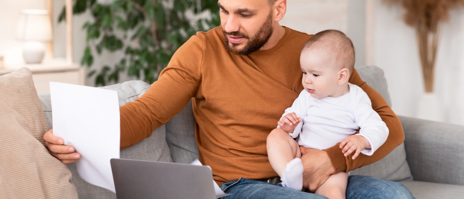 Papa füllt Anträge nach der Geburt am Tablet aus.