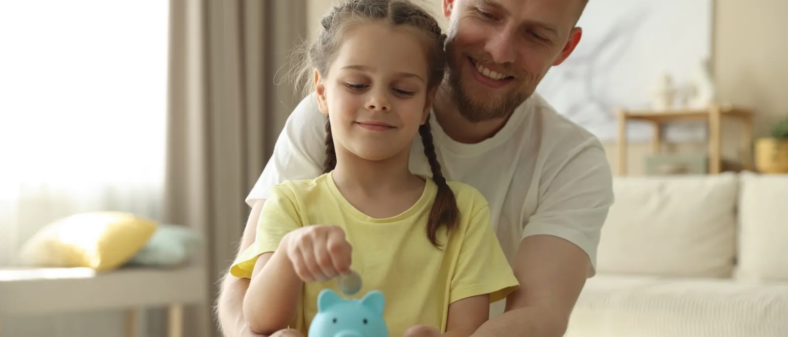 Ein Papa legt zusammen mit der Tochter Geld ins Sparschwein